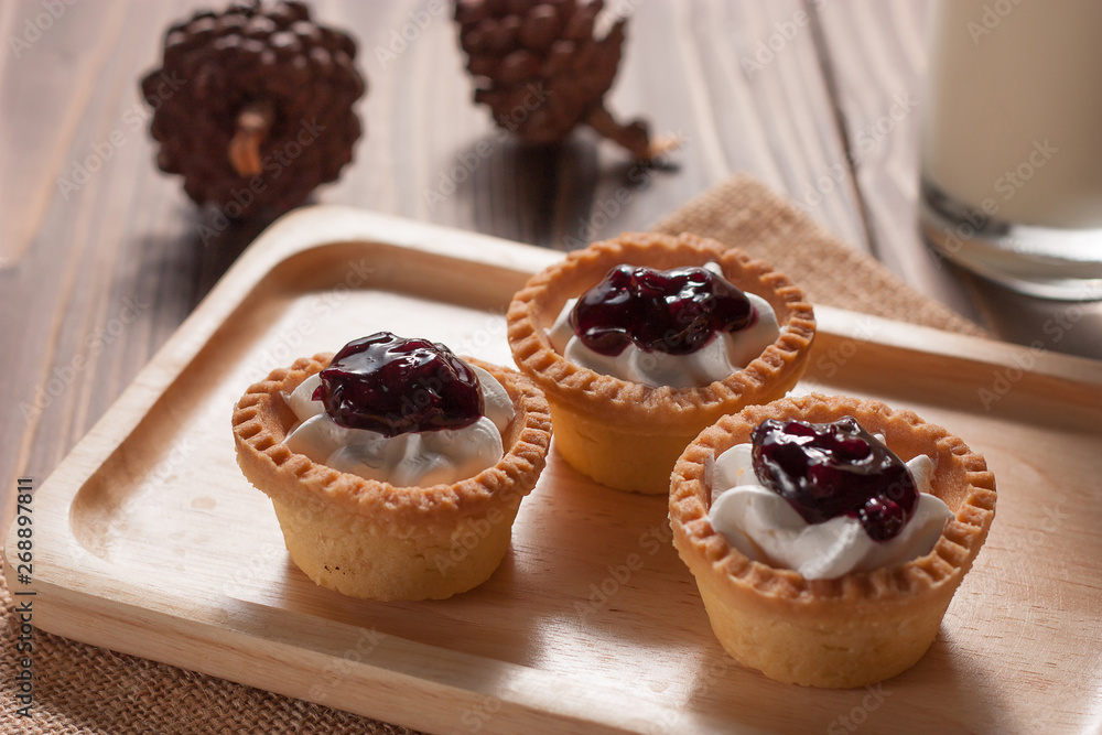 Delicious homemade mini berry tarts and custard on wood cutting board Delicious homemade mini berry tarts and custard on wood cutting board