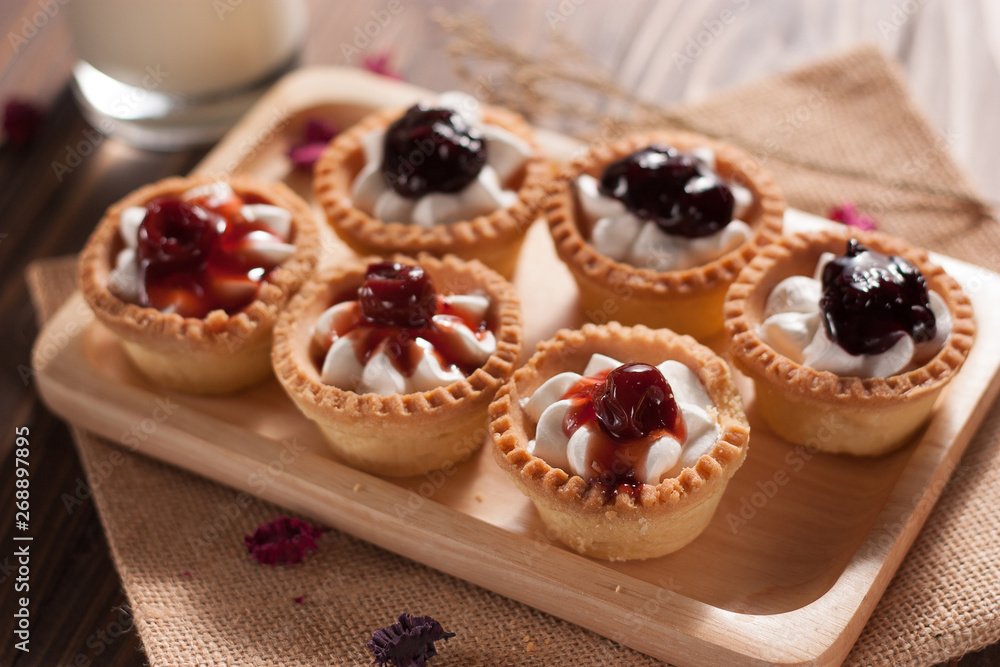 Delicious homemade mini berry tarts and custard on wood cutting board Delicious homemade mini berry tarts and custard on wood cutting board