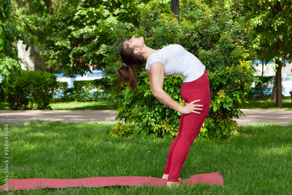 Beautiful attractive young woman stretching exercising in the park.