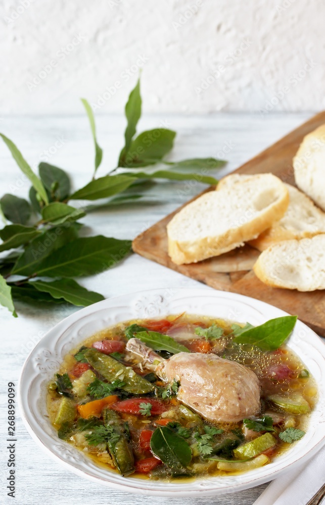 Vegetable soup with chicken with bay leaf in a white plate on a light background. laurel as an aromatic spice in a dish. Soft focus. Place for text. Copy Space Vegetable soup with chicken with bay leaf in a white plate on a light background. laurel as an aromatic spice in a dish. Soft focus. Place for text. Copy Space