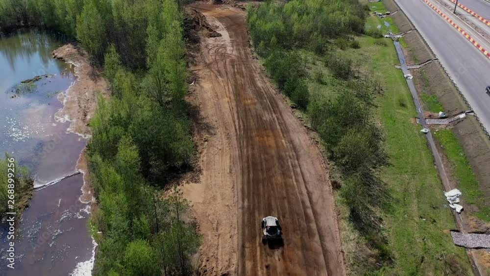 Buggy racing on the track in the forest next to the road and the lake. Aerial view. Shooting from the drone. Buggy racing on the track in the forest next to the road and the lake. Aerial view. Shooting from the drone.