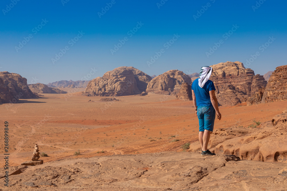 A tourist standing by the look out of a panoramic view of the desert in Wadi Rum, Jordan, Middle East.