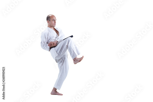 Young athlete with black belt is training karate exercises on isolated white background