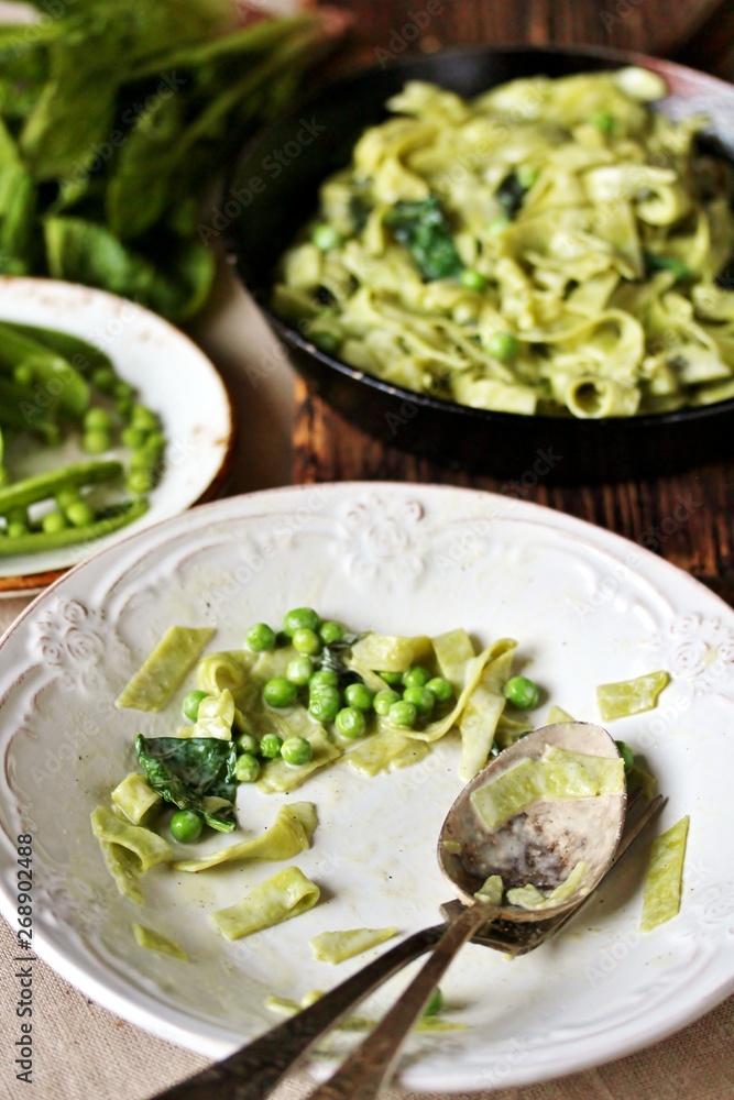 the process of eating pasta fettuccine with spinach leaves and green peas. Dirty dishes. vegetarian cuisine. Italian food. the process of eating pasta fettuccine with spinach leaves and green peas. Dirty dishes. vegetarian cuisine. Italian food.