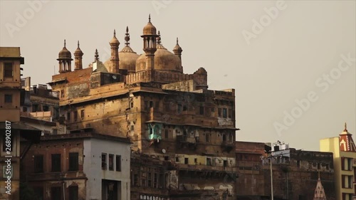 Close-up low-angle still shot of the historical Alamgir Mosque and other old Varanasi city buildings at the riverbank, Ganga River, India photo