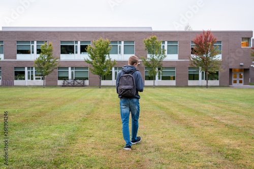 Student walking through a soccer field next to a high school.
