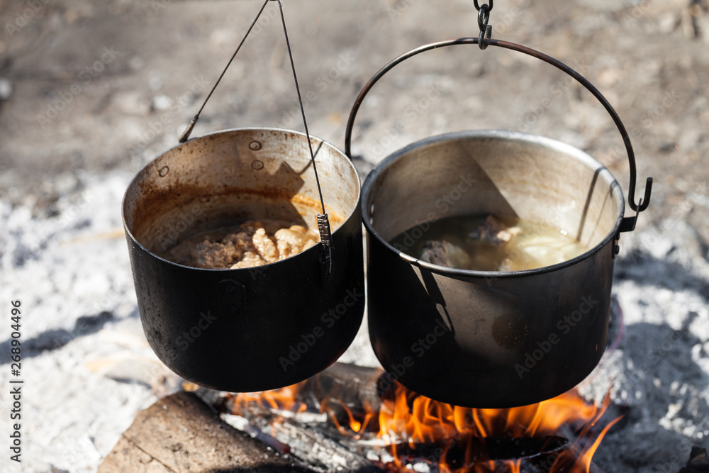 Cooking in two sooty old pots on campfire Cooking in two sooty old pots on campfire