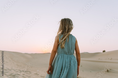 Little girl standing in the desert admiring the sunset