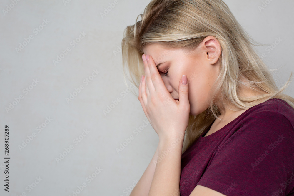 Depressed crying blonde woman cover her face with hands. Space for text Depressed crying blonde woman cover her face with hands. Space for text