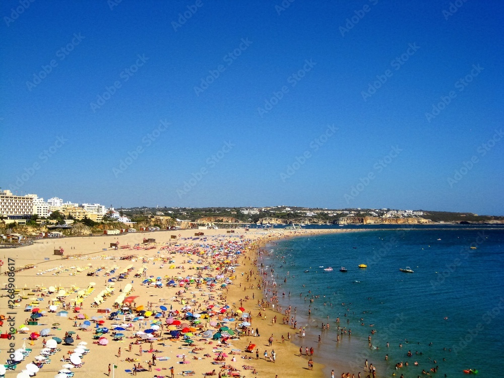 View from the cliffs to the people, tourists on the sandy beach Praia da Rocha at Portimao. Algarve beach during the summer vacation, Portugal, Europe.