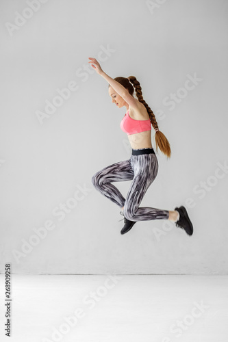 Fototapeta Naklejka Na Ścianę i Meble -  A young girl jumps high. The concept of sports, healthy lifestyle, fitness, stretching.