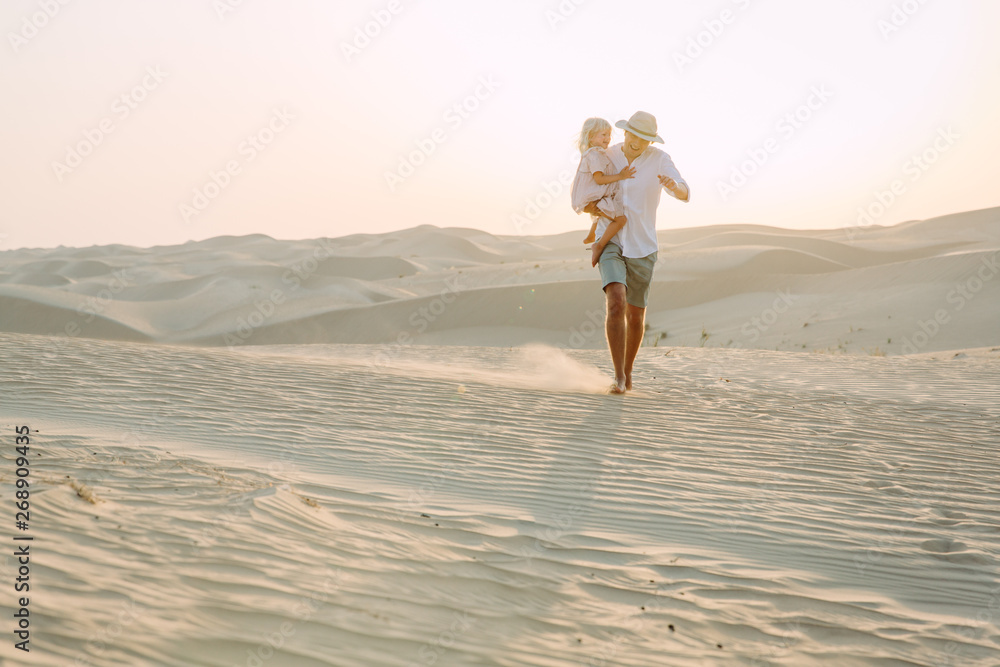 Fototapeta premium Father holding his little daughter in the desert in Dubai
