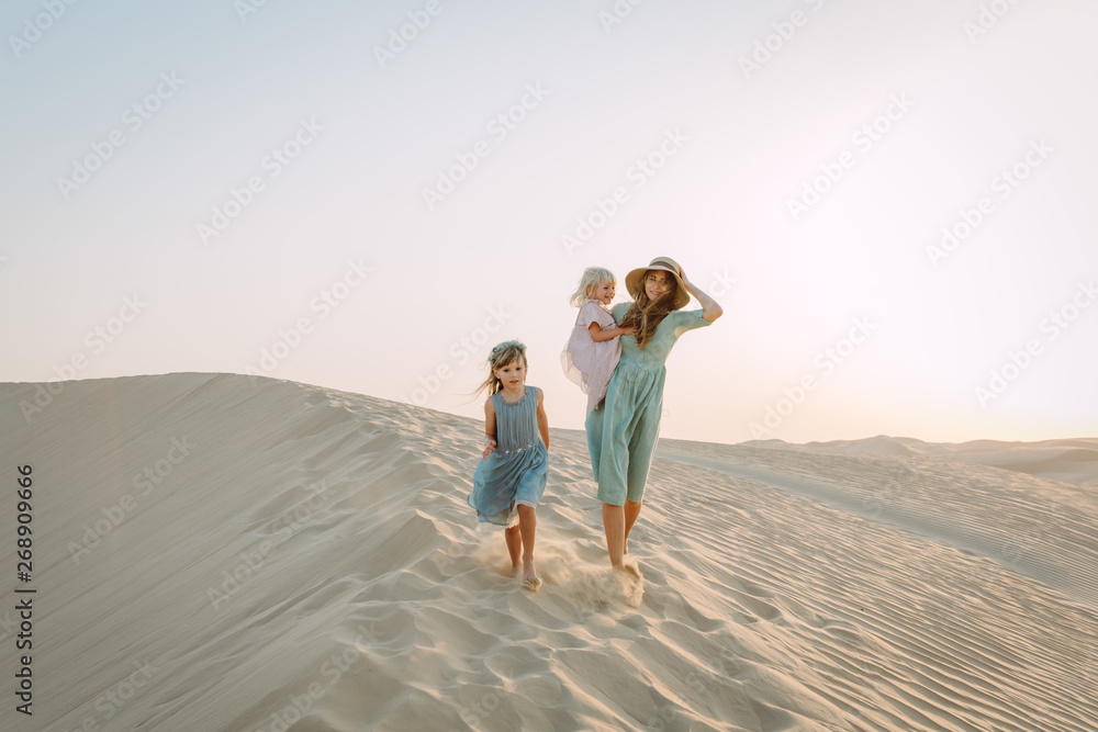 Young beautiful mother with two little daughters in the desert in Dubai