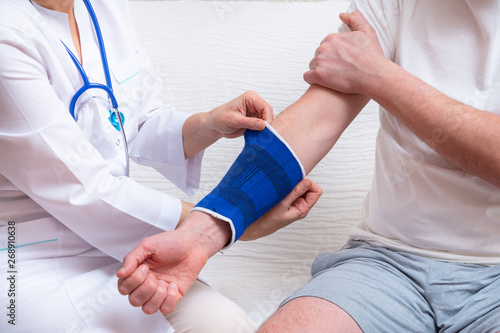 doctor helps the patient to use bandage on the elbow