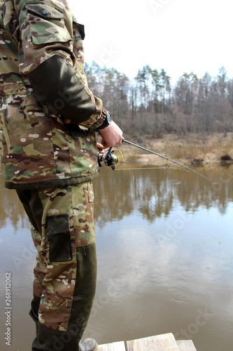 Angler in camouflage clothing, fishing on spinning
