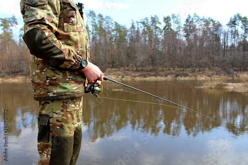 Fisherman in camouflage clothing, fishing on spinning.