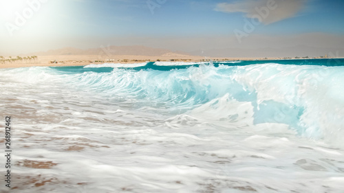 Beautiful image of turquoise sea waves rolling over the shore at bright sunny day