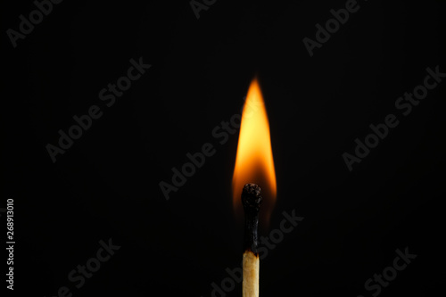 Lit match on black background, closeup. Space for text