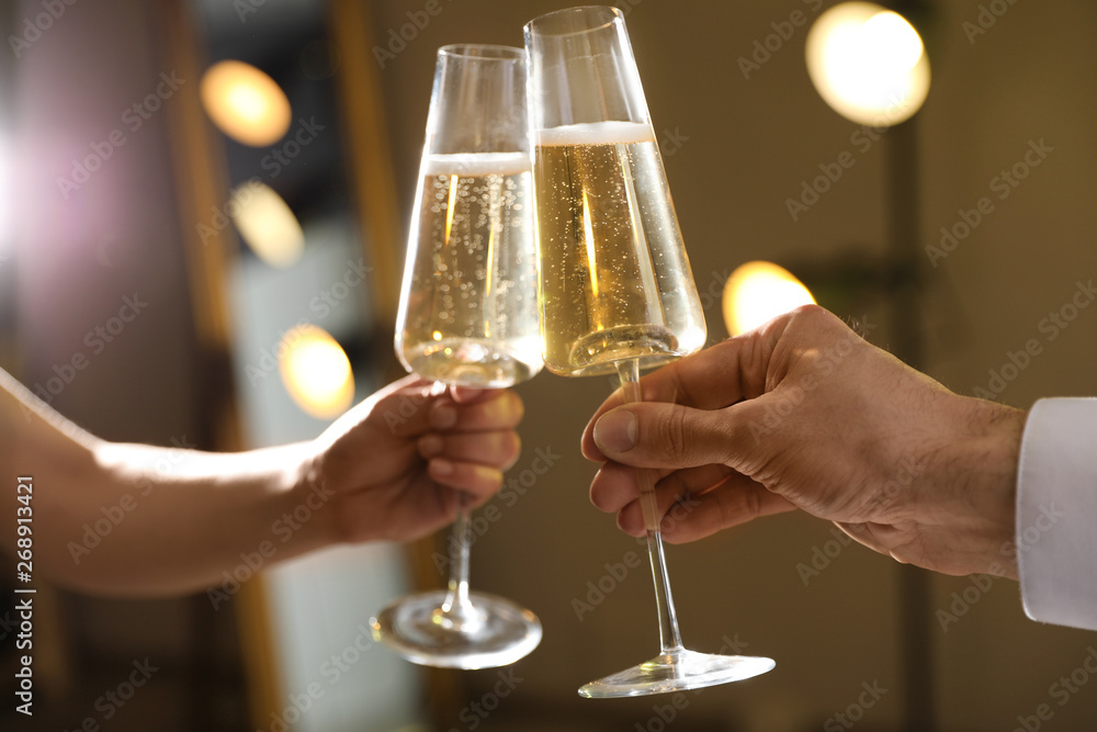 Man and woman clinking glasses of champagne on blurred background, closeup