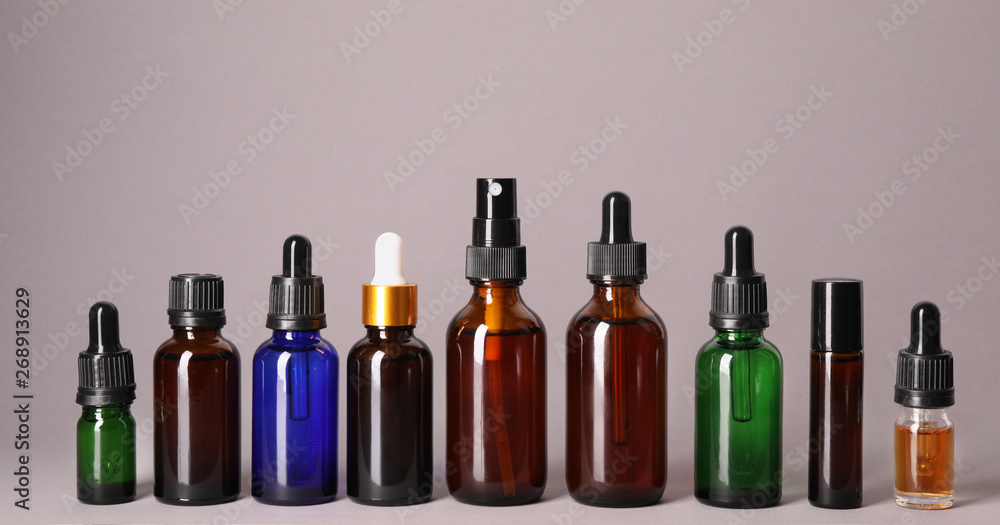 Cosmetic bottles of essential oils on color background Cosmetic bottles of essential oils on color background