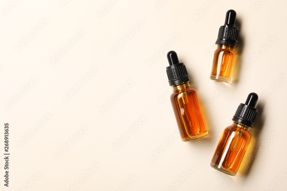Cosmetic bottles of essential oils and space for text on color background, flat lay Cosmetic bottles of essential oils and space for text on color background, flat lay