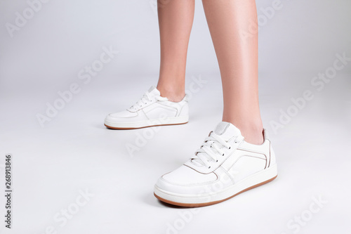 Woman in stylish sport shoes on light background