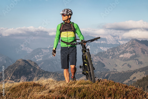 Obraz na płótnie Male mountainbiker walking with his bike on a trail in the mountains w salonie