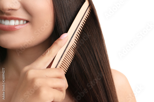 Young woman with wooden hair comb on white background, closeup