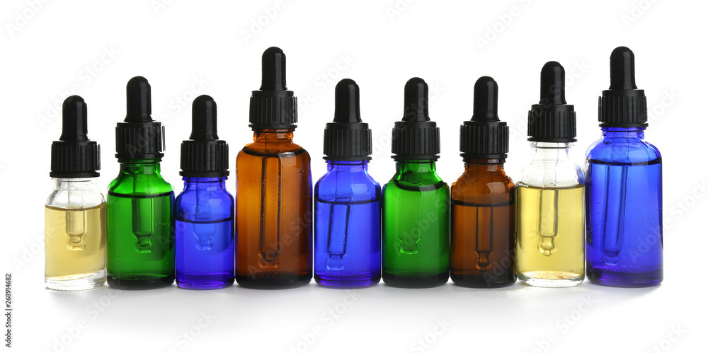 Different little bottles with essential oils on white background