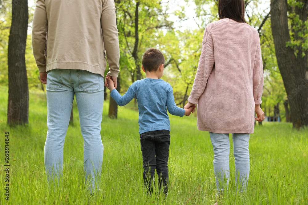 Little child holding hands with his parents in park. Family weekend Little child holding hands with his parents in park. Family weekend