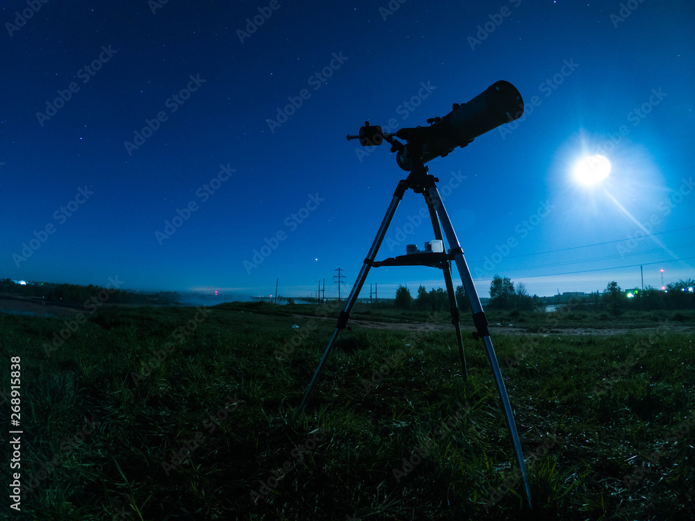 Telescope on a tripod at night in nature against the backdrop of the starry sky.