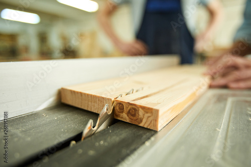 Closeup of unrecognizable carpenter cutting wood using disksaw in joinery workshop, copy space
