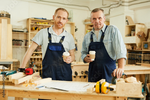 Waist up portrait of two carpenters looking at camera while standing in joinery workshop, copy space