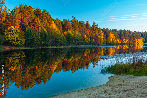 Silence at the forest lake at sunset, with reflection of sky and forest on a water smooth surface, Russia, Mari El