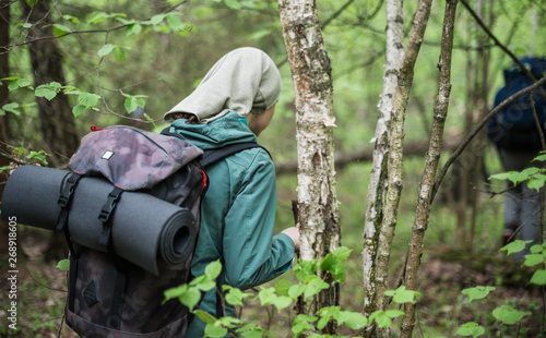 A woman with a backpack and with a stick walking along a forest