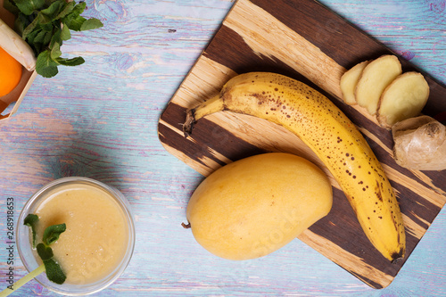 Fototapeta Naklejka Na Ścianę i Meble -  recepie of healthy fresh yellow fruit mango smoothie at blue table