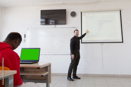 Wallpaper Mural Male professor explain lesson to students and interact with them in the classroom.Helping a students during class. University student being helped by male lecturer during class. Torontodigital.ca