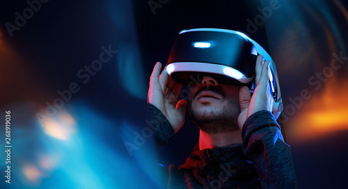 Model young man with beard in glasses of virtual reality. Augmented reality,  future technology concept. VR. Neon light. photo