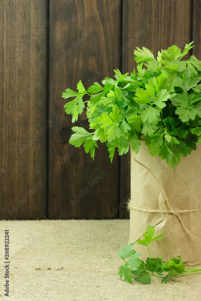 Green parsley in a paper glass on a wooden texture. 