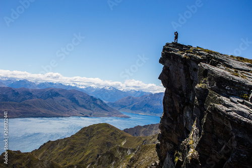 Hiker on the top of mountain, lake Hawea in the background, south island, New Zealand.