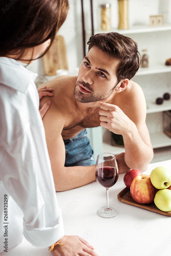 selective focus of brunette girl looking at handsome muscular man in kitchen selective focus of brunette girl looking at handsome muscular man in kitchen