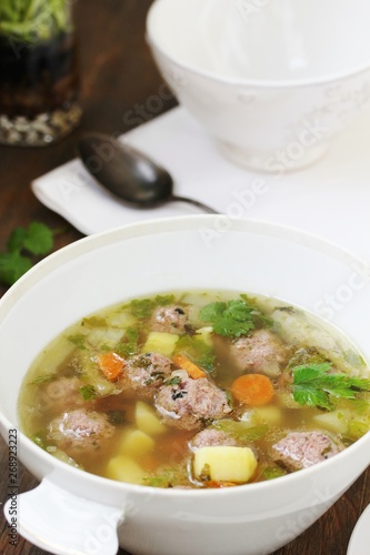 soup with meatballs in a white bowl. light soup with pork meatballs.