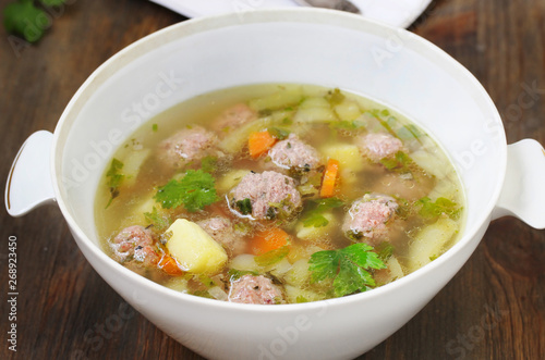 soup with meatballs in a white bowl. light soup with pork meatballs.