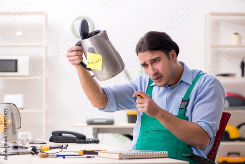 Young man repairing kettle in service centre 