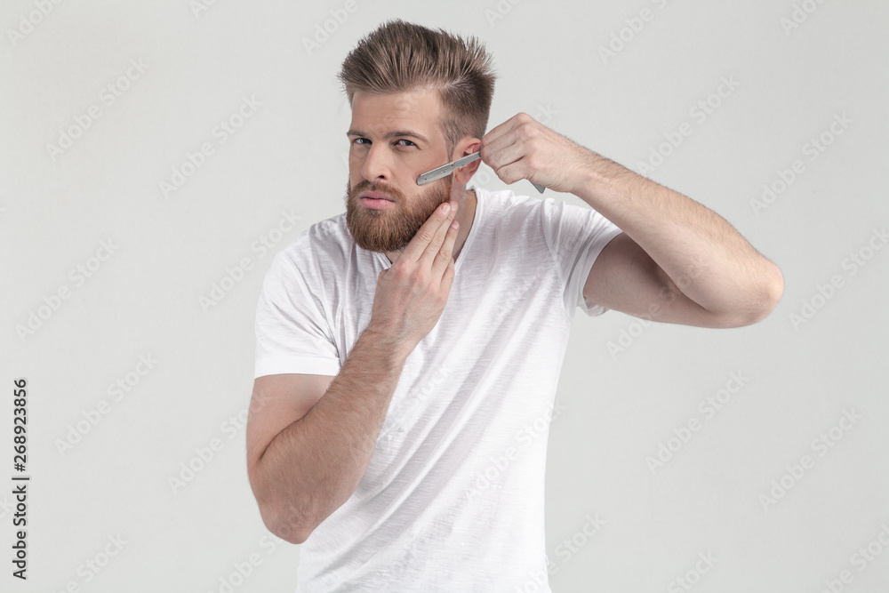 Successful man with lush ginger beard. prick up the cans on the beard looking at the camera. dressed in casual clothes. stand in front of the white background Successful man with lush ginger beard. prick up the cans on the beard looking at the camera. dressed in casual clothes. stand in front of the white background