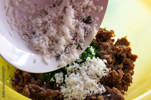 Add rice to the minced meat. Rice on a white plate. Rice on a white plate and minced meat in a container. she puts the rice in minced meat