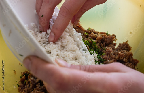 Add rice to the minced meat. Rice on a white plate. Rice on a white plate and minced meat in a container. she puts the rice in minced meat