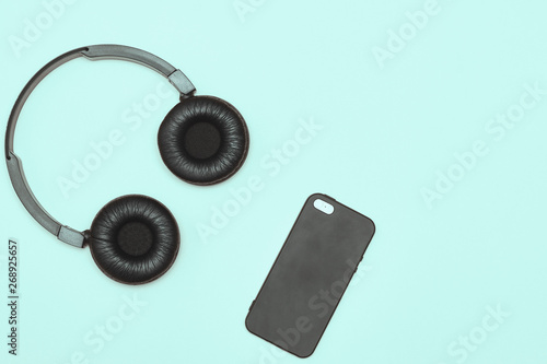 Modern black wireless headphones on a blue background. The concept of music and fashion. Minimalism. copy space. space for text