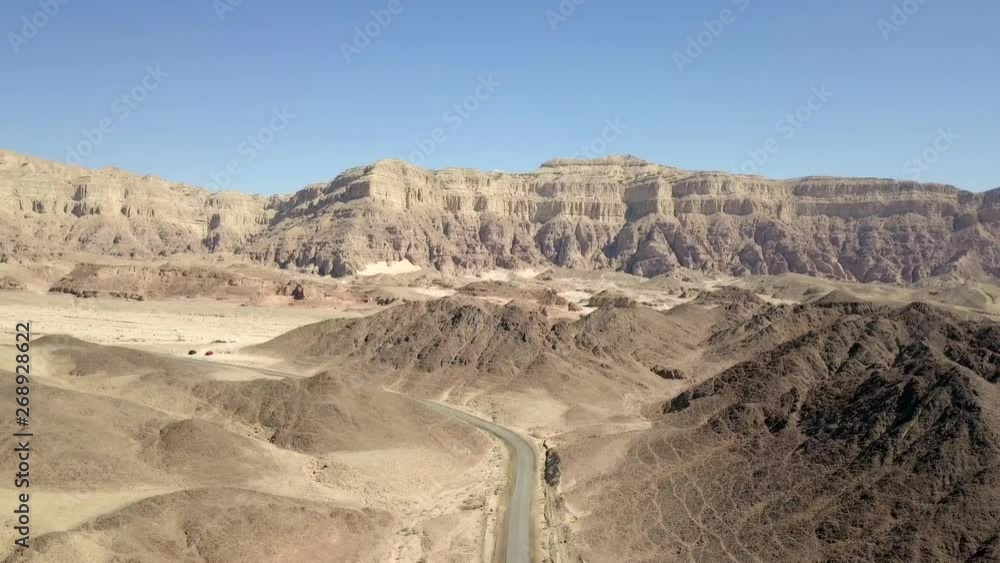 Long stretch of an old Desert road with mountains and blue sky in the background, Aerial footage. Long stretch of an old Desert road with mountains and blue sky in the background, Aerial footage.