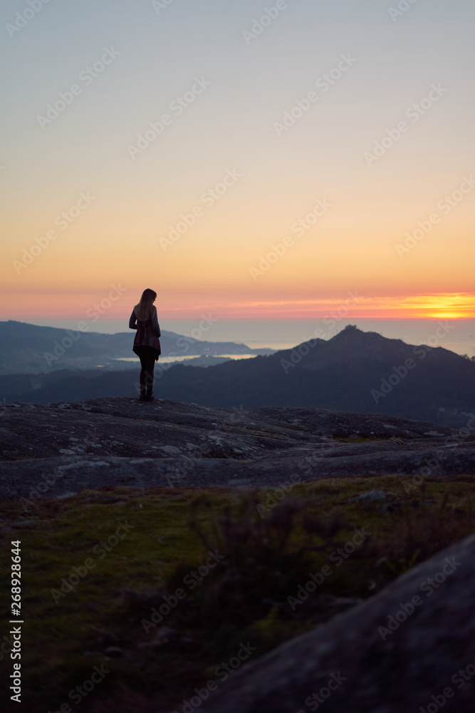 Silhouette of a woman contemplating the sunset from Mount Galiñeiro in Vigo, Galicia, Spain